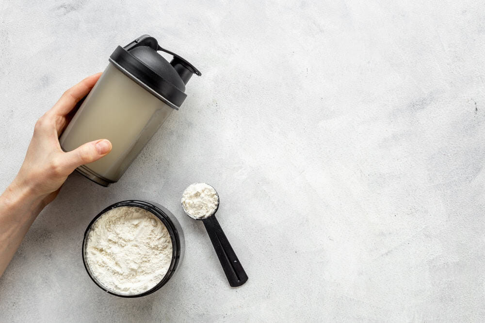 Sport,Shaker,Bottle,In,Hands,And,Whey,Protein,In,Jar.